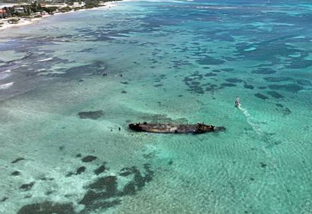 Aerial view of a shallow Aruba shipwreck snorkel site with swimmers and a boat nearby